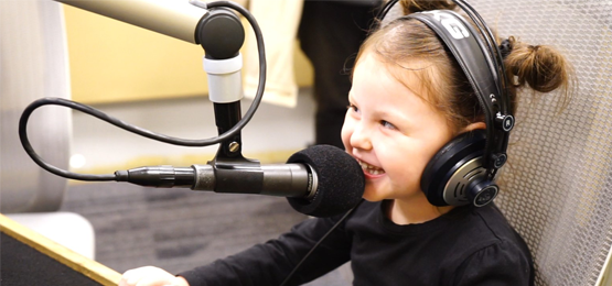 Young girl speaking in to the radio microphone and wearing headphones